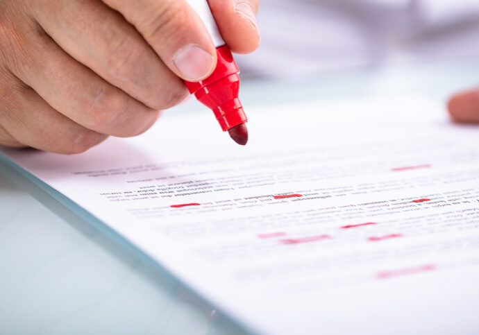 Close-up Of A Businessperson's Hand Holding Marker On Document